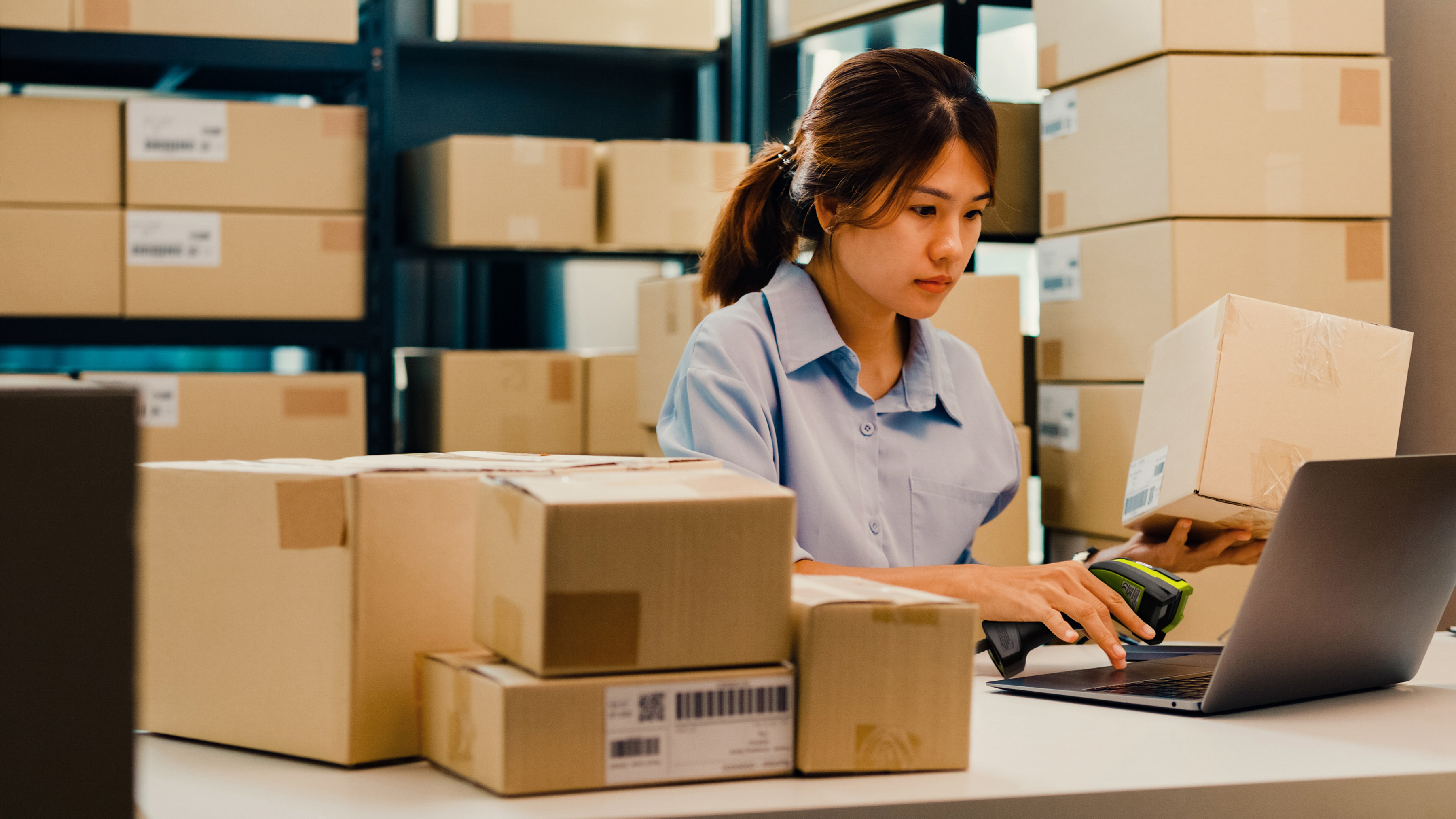 An employee handling box deliveries using a Zebra handheld barcode scanner.